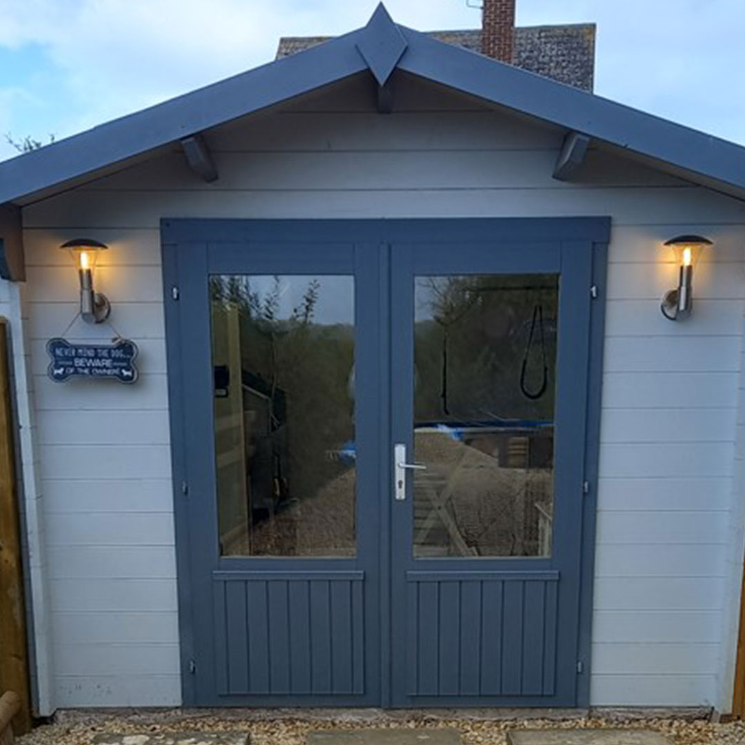 The Serene Dog Grooming studio exterior at Border Cottage, with blue-grey doors and signage